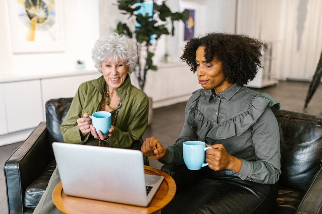 Two professional women collaborate during a video conference in a modern office setting.