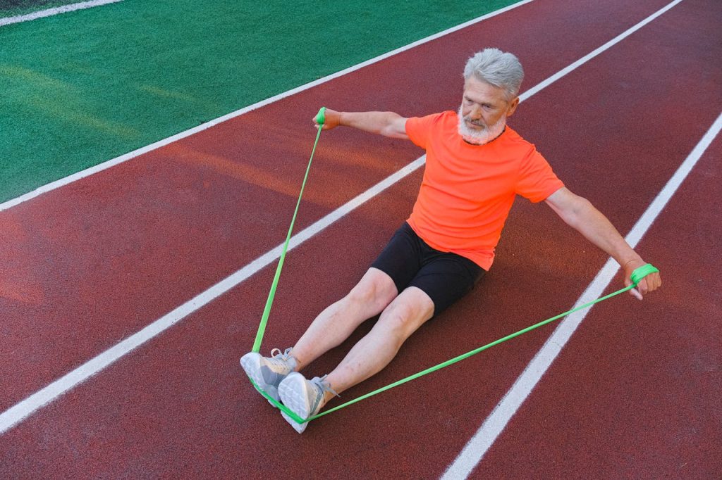 Elderly man exercising on a track with a resistance band, showcasing strength and fitness.